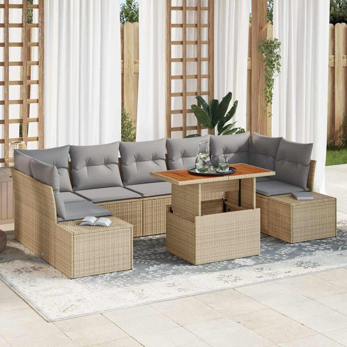 Juego de patio exterior con mimbre marrón claro, cojines grises y mesa de madera. Cortinas blancas y alfombra estampada.