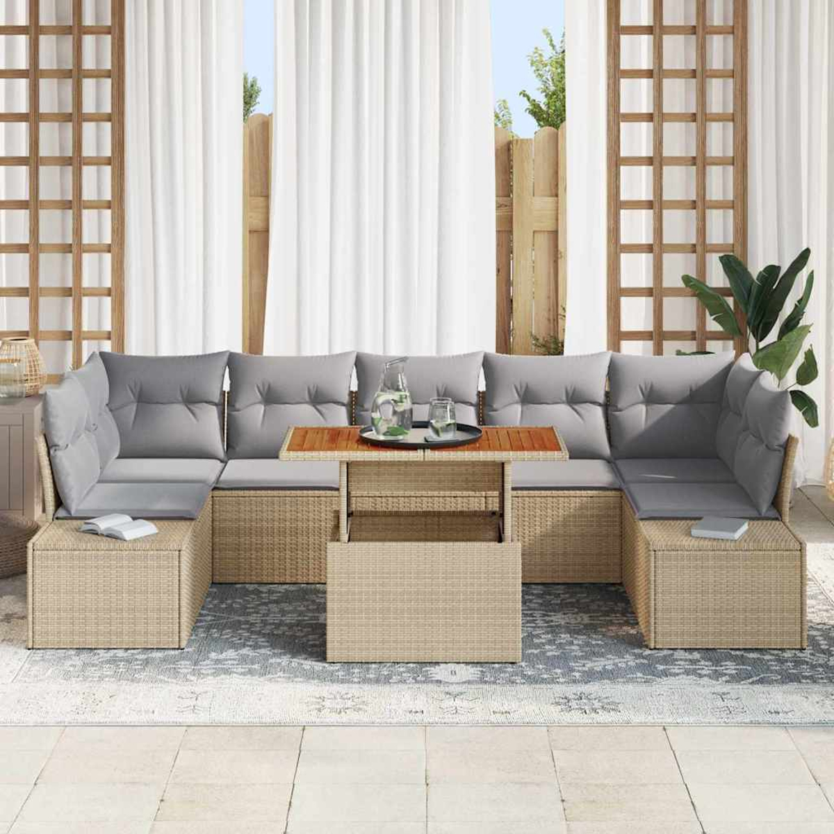 Sofá seccional exterior de mimbre con cojines grises, una mesa de centro y cortinas blancas. Detrás del sofá hay una valla y un enrejado de madera.