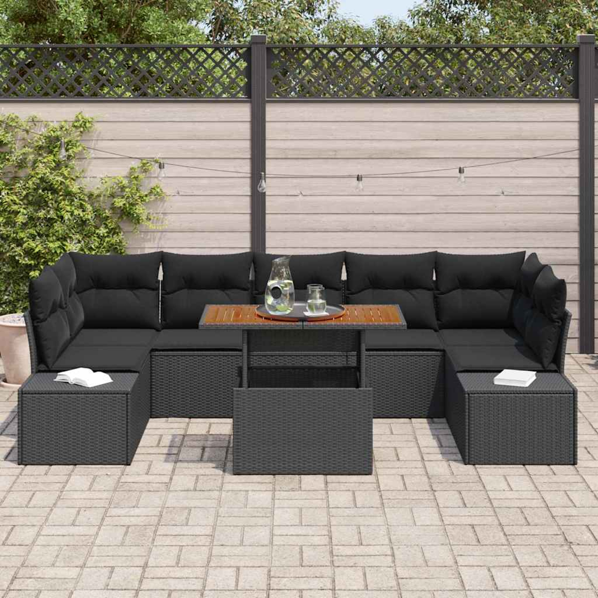 Outdoor-Ecksofa mit schwarzen Kissen, einem Holztisch und zwei Ottomanen. Die Szene spielt auf einer gepflasterten Terrasse, mit Holzzaun im Hintergrund.