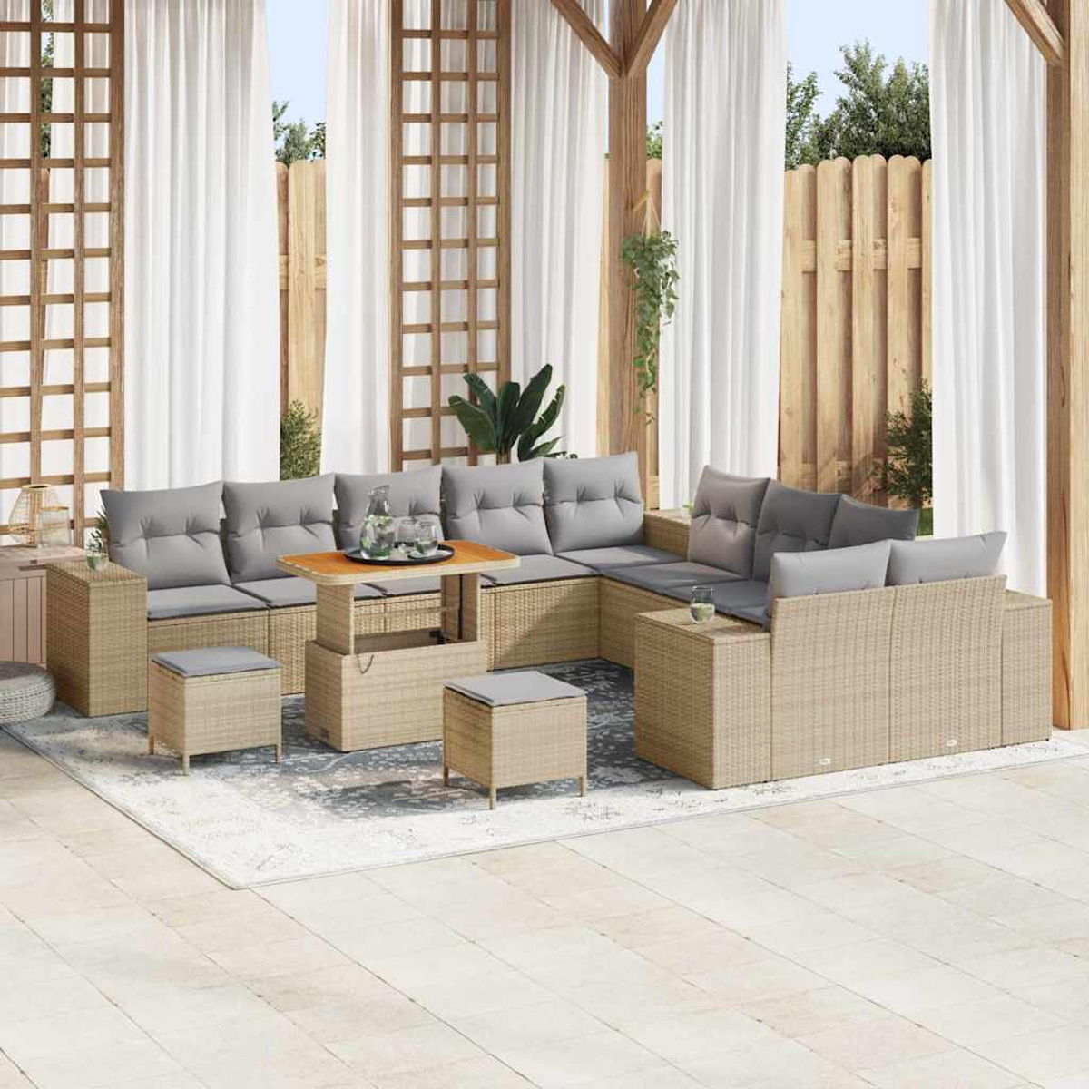 Outdoor-Sofa aus Korbgeflecht mit grauen Kissen, einem Holztisch und zwei Hockern. Weiße Vorhänge und ein Holzzaun sind im Hintergrund.