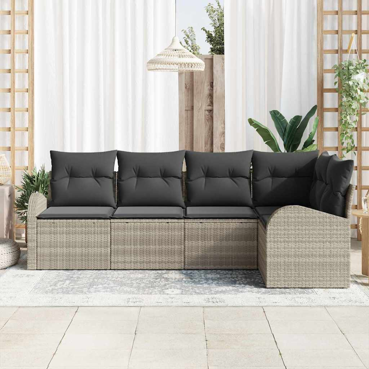 Graues Outdoor-Ecksofa mit dunkelgrauen Kissen auf einer Terrasse. Weiße Vorhänge und Pflanzen im Hintergrund.