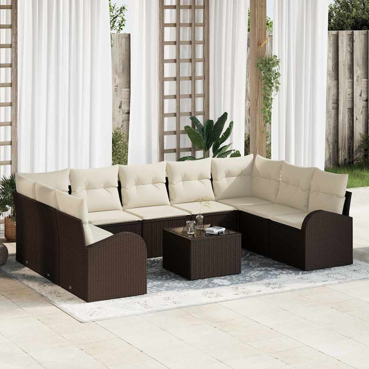Garten-Sitzgruppe mit braunen Korbgitterrahmen, cremefarbenen Kissen und einem quadratischen Couchtisch auf einem gemusterten Teppich vor weißen Vorhängen.