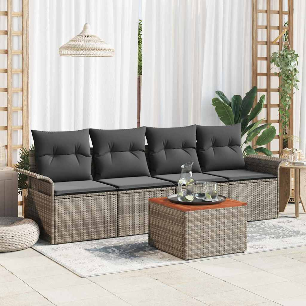 Gartenmöbel mit grauen Kissen und einem passenden Couchtisch. Eine Kanne mit Gläsern auf dem Tisch. Weiße Vorhänge im Hintergrund.