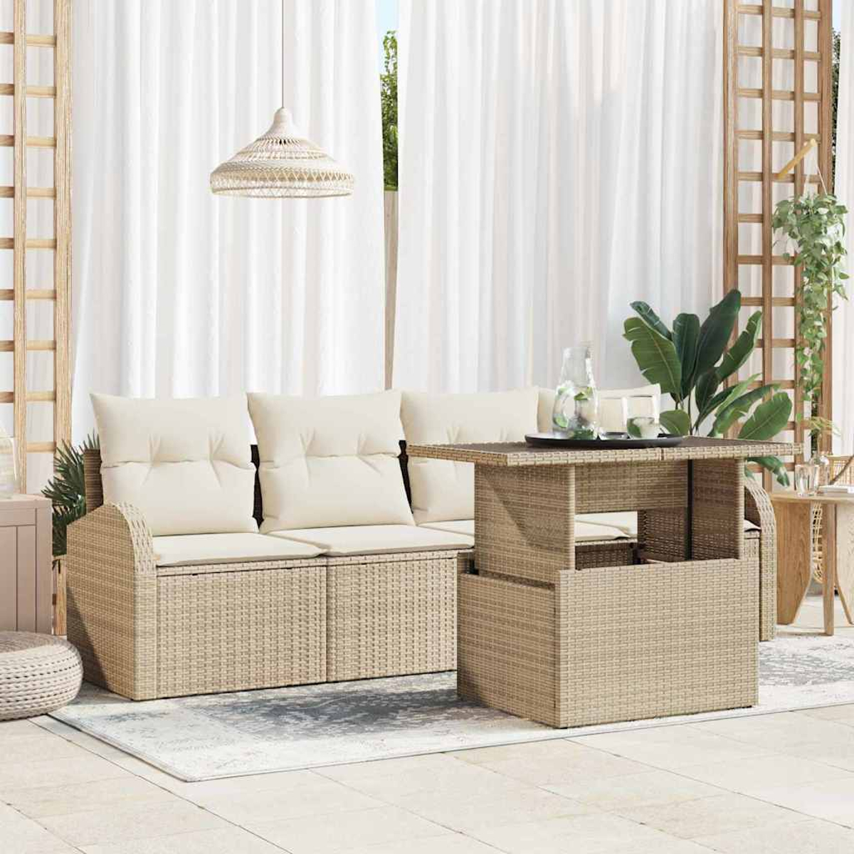 Geflochtenes Sofa und Tisch auf einer Terrasse. Weiße Vorhänge, eine Hängelampe und Pflanzen sind im Hintergrund.