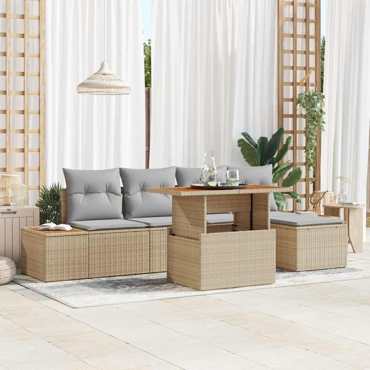 Garten-Sitzgruppe mit Sofa, Tisch und Hocker. Graue Kissen, Rattanmöbel und weiße Vorhänge im Hintergrund.