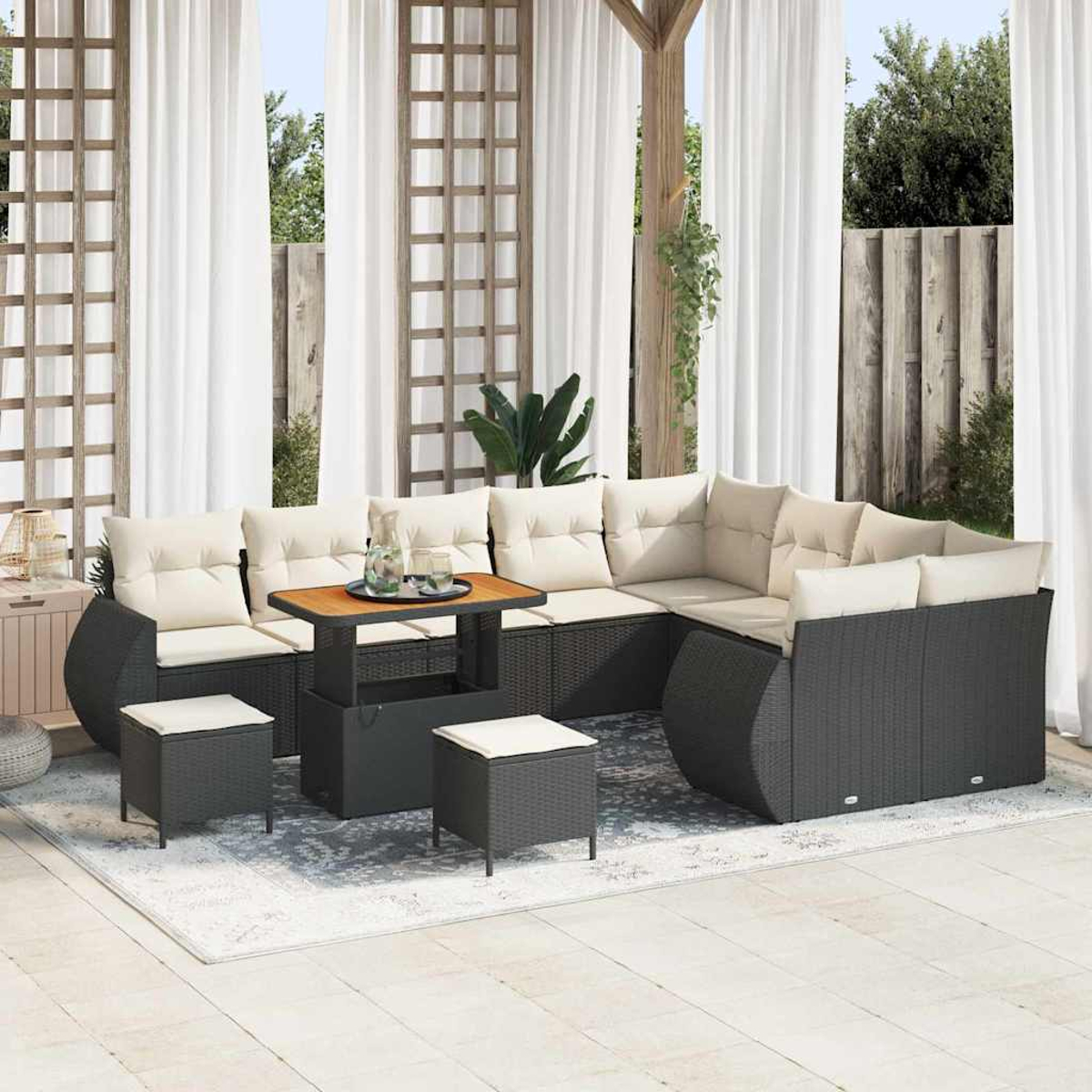 Terrassenset im Freien mit dunkelgrauen gewebten Sitzgelegenheiten, cremefarbenen Kissen und einem kleinen Tisch. Der Hintergrund umfasst weiße Vorhänge und üppiges Grün.