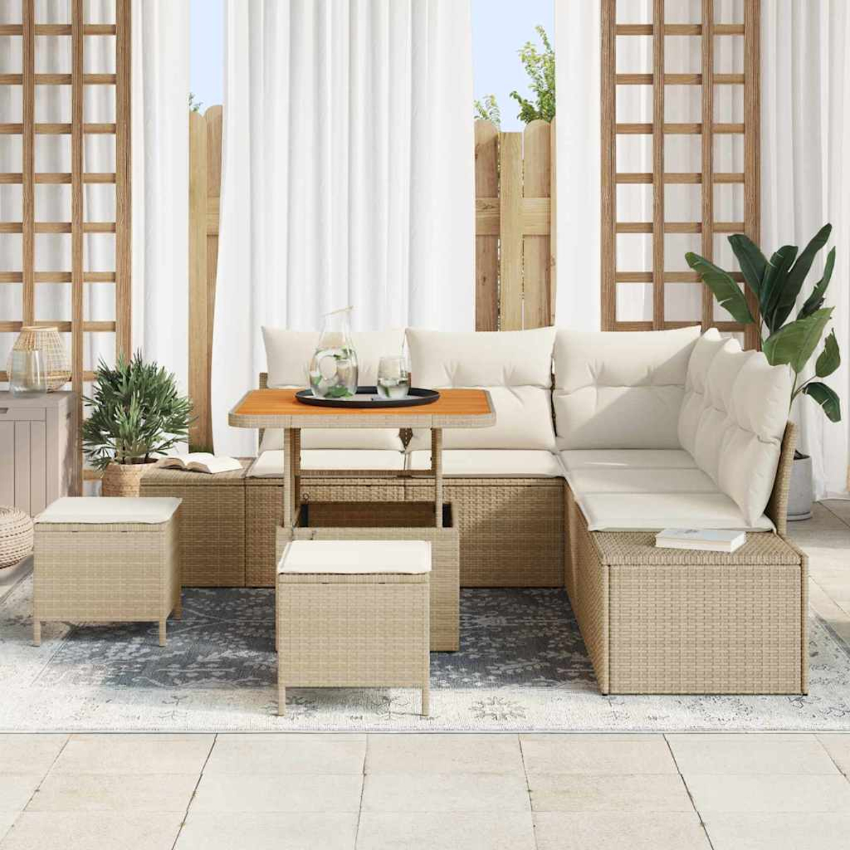 Terrassenset im Freien. Beige Rattan-Ecksofa und Hocker mit weißen Kissen, einem Tisch und Pflanzen. Weiße Vorhänge im Hintergrund.