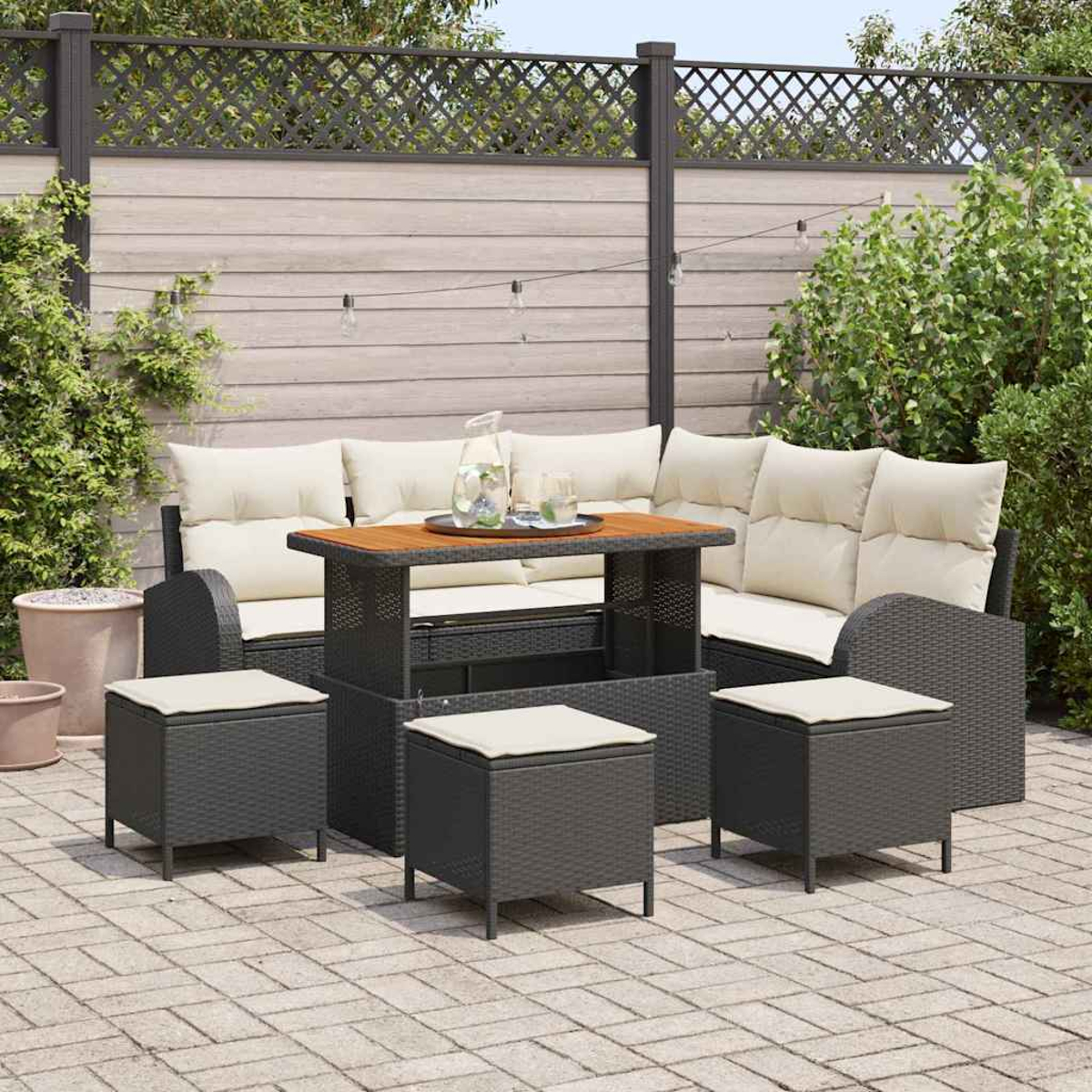 Garten-Terrassenset mit Tisch, Sofa und Hockern. Das Set steht auf einer Ziegelterrasse, mit Zaun und Grün bedeckt.
