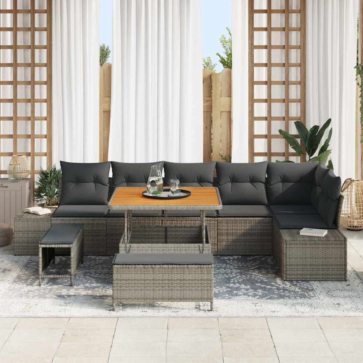 Outdoor-Sitzgruppe mit grauen Kissen und einem Holztisch. Vorhänge und ein Holzgitter im Hintergrund. Auf dem Boden liegt ein Teppich.