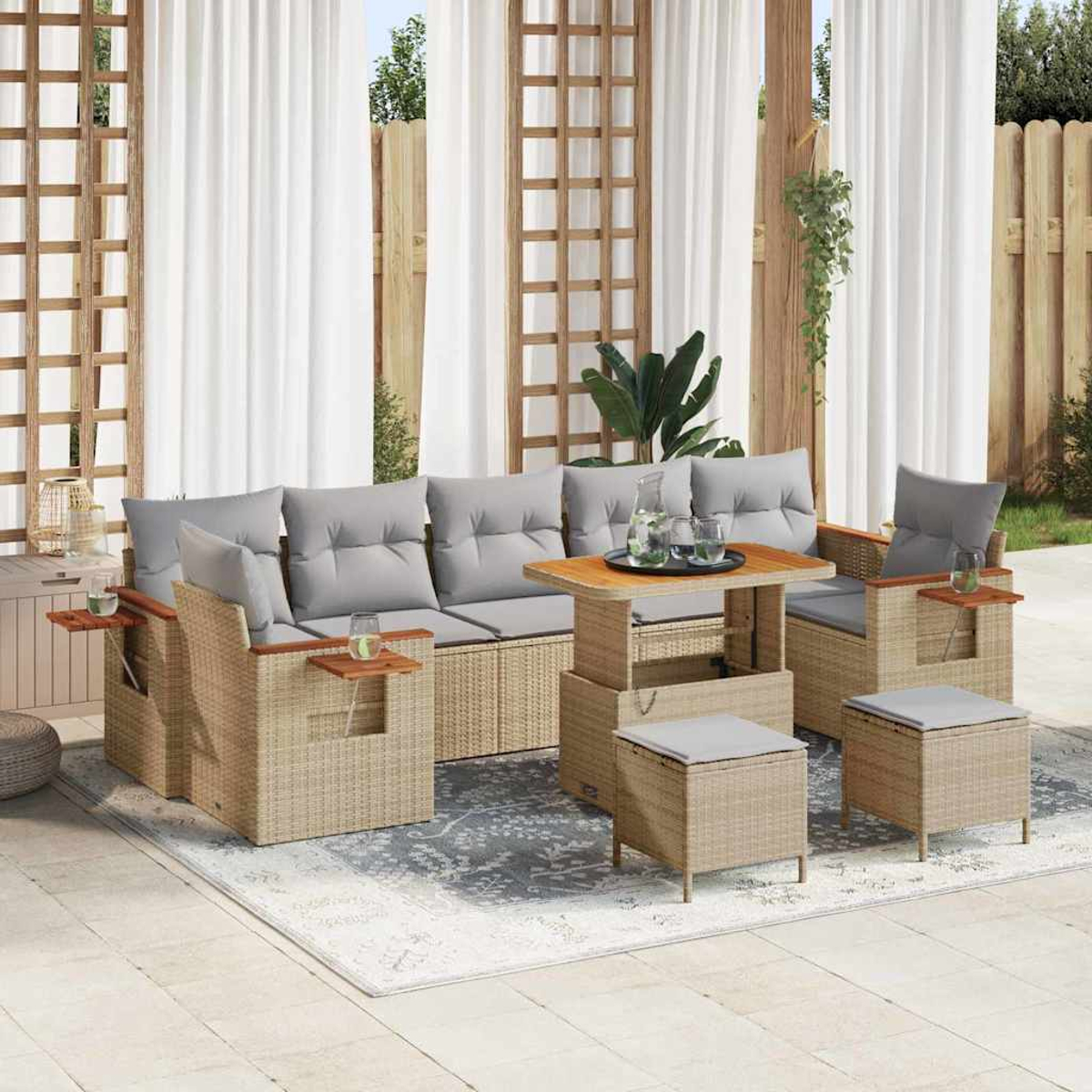 Rattan-Gartenmöbel-Set mit Sofa, Stühlen und Ottomanen. Graue Kissen, Holztisch und weiße Vorhänge im Hintergrund.