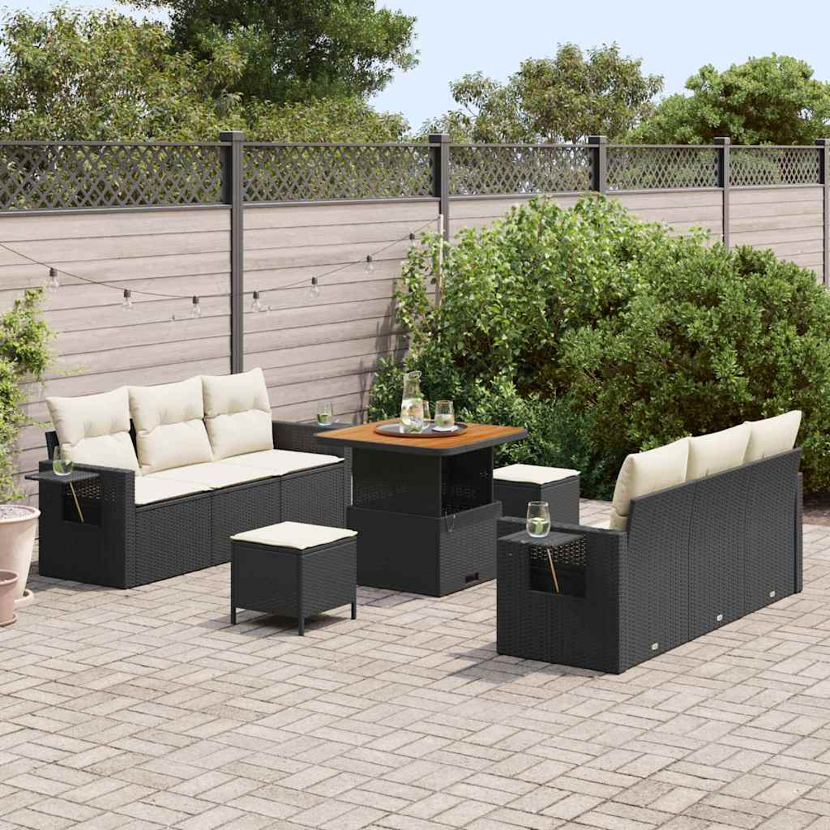 Terrassenset mit schwarzen Korbmöbeln, beigen Kissen, Holztisch und dekorativem Zaun im Hintergrund.