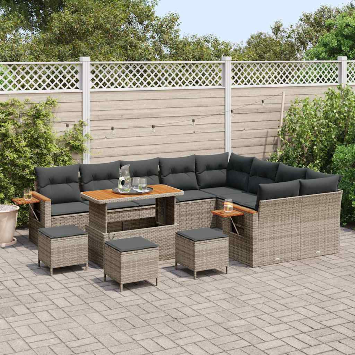 Outdoor-Ecksofa mit grauen Kissen und einem Holztisch. Drei Hocker und ein Zaun im Hintergrund.