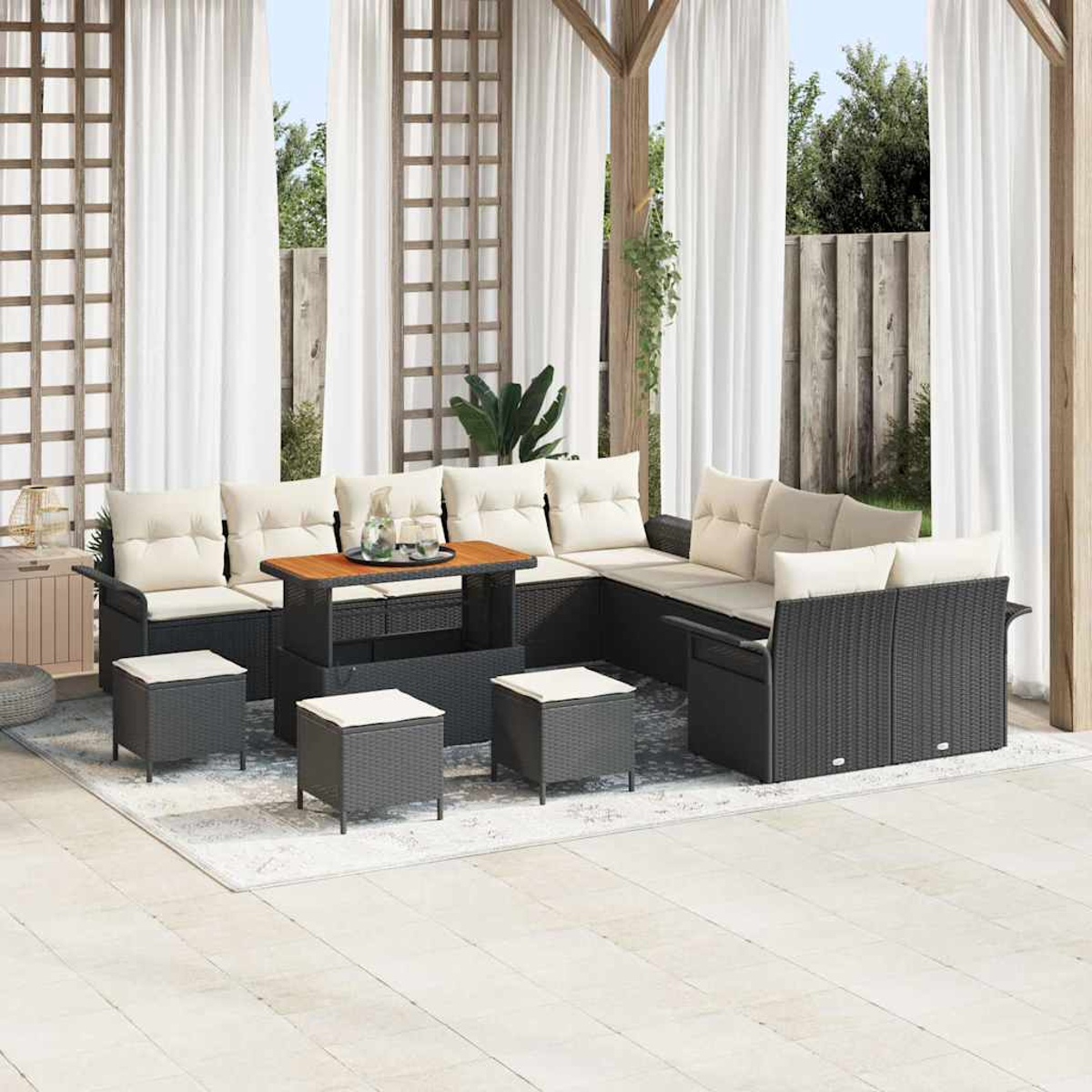 Gartenmöbel-Set mit Ecksofa, Ottomanen und Tisch. Weiße Vorhänge und Holzkonstruktion im Hintergrund.
