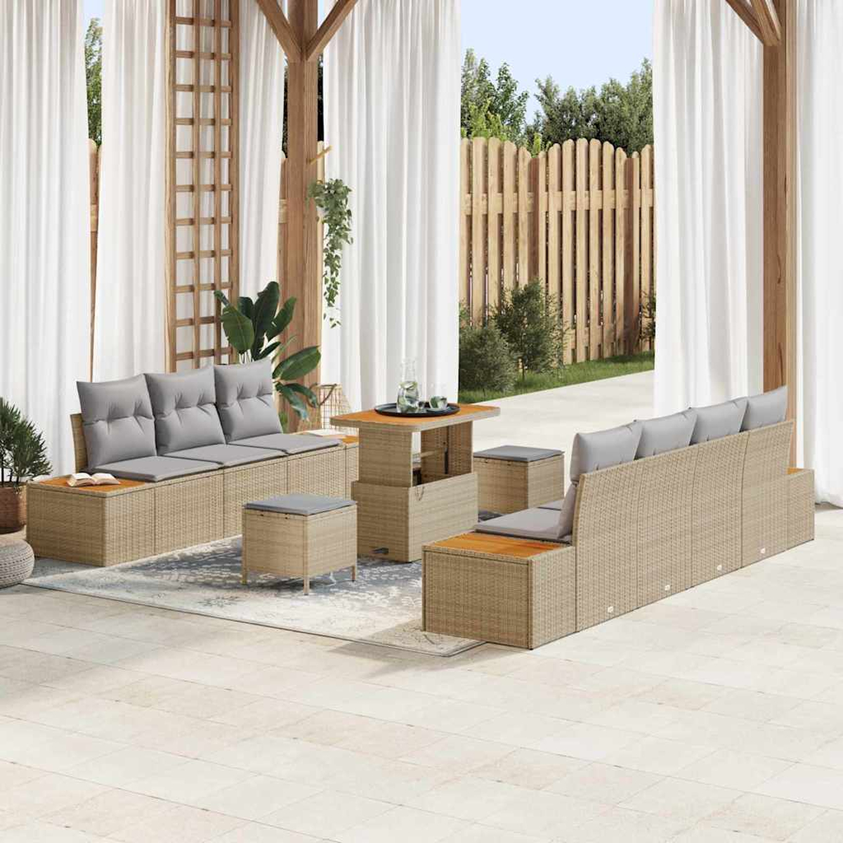 Terrassenset: beige Korbsessel, Tisch und Hocker mit grauen Kissen. Weiße Vorhänge und Holzzaun im Hintergrund.