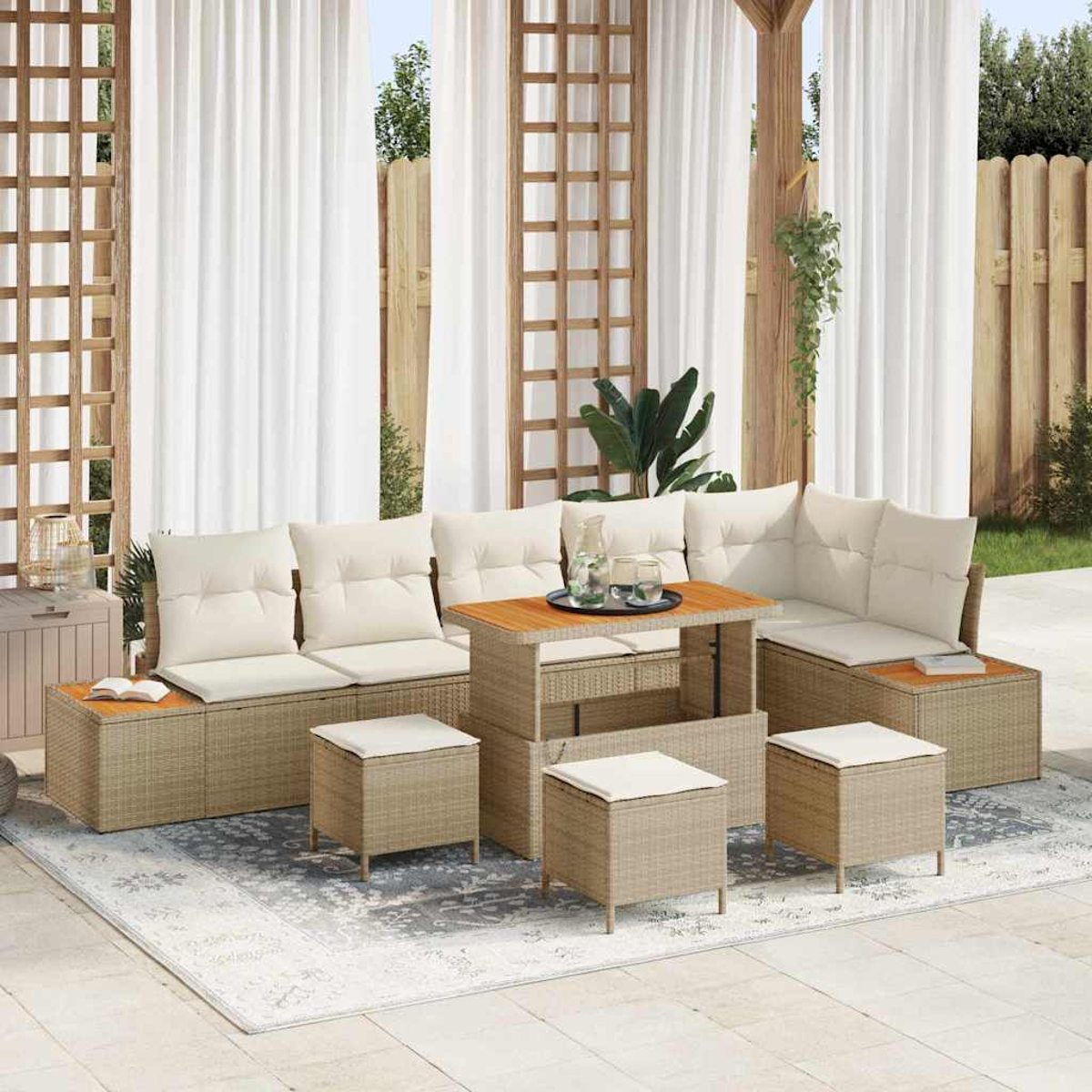 Set da esterno: mobili in vimini beige con cuscini color crema. Include un divano, pouf e un tavolo, su un tappeto fantasia.