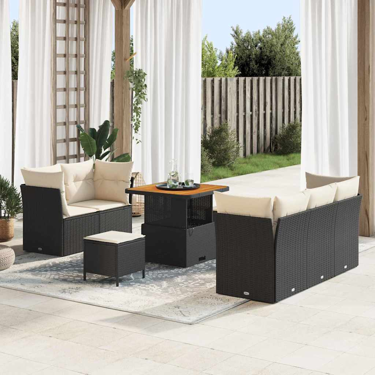 Gartenmöbel-Set für die Terrasse. Schwarze Korbsessel mit cremefarbenen Kissen, quadratischer Tisch und Hocker auf gemustertem Teppich.