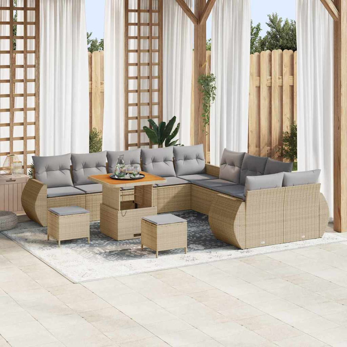 Außenbereich mit Rattan-Sofa, grauen Kissen, Holztisch und Vorhängen. Enthält zwei Hocker und einen Teppich.