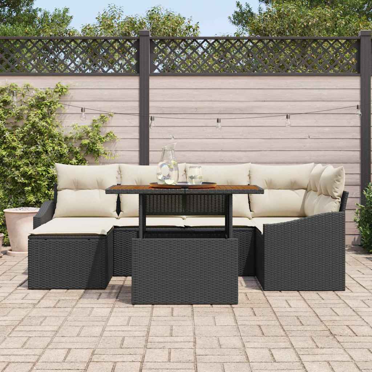 Terrassenset: dunkelgraues Korbmöbel mit cremefarbenen Kissen, Holztisch und Zaun im Hintergrund.