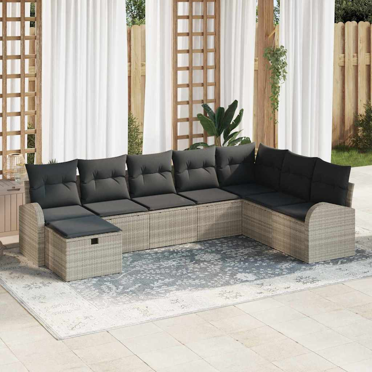 Outdoor-Ecksofa mit grauen Kissen auf einem gemusterten Teppich, in der Nähe von weißen Vorhängen und Holzgitter.