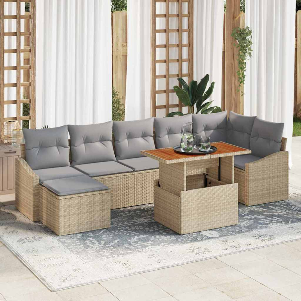 Outdoor-Wicker-Möbel-Set mit grauen Kissen, einem Holztisch und einem gemusterten Teppich auf einer Terrasse mit weißen Vorhängen.