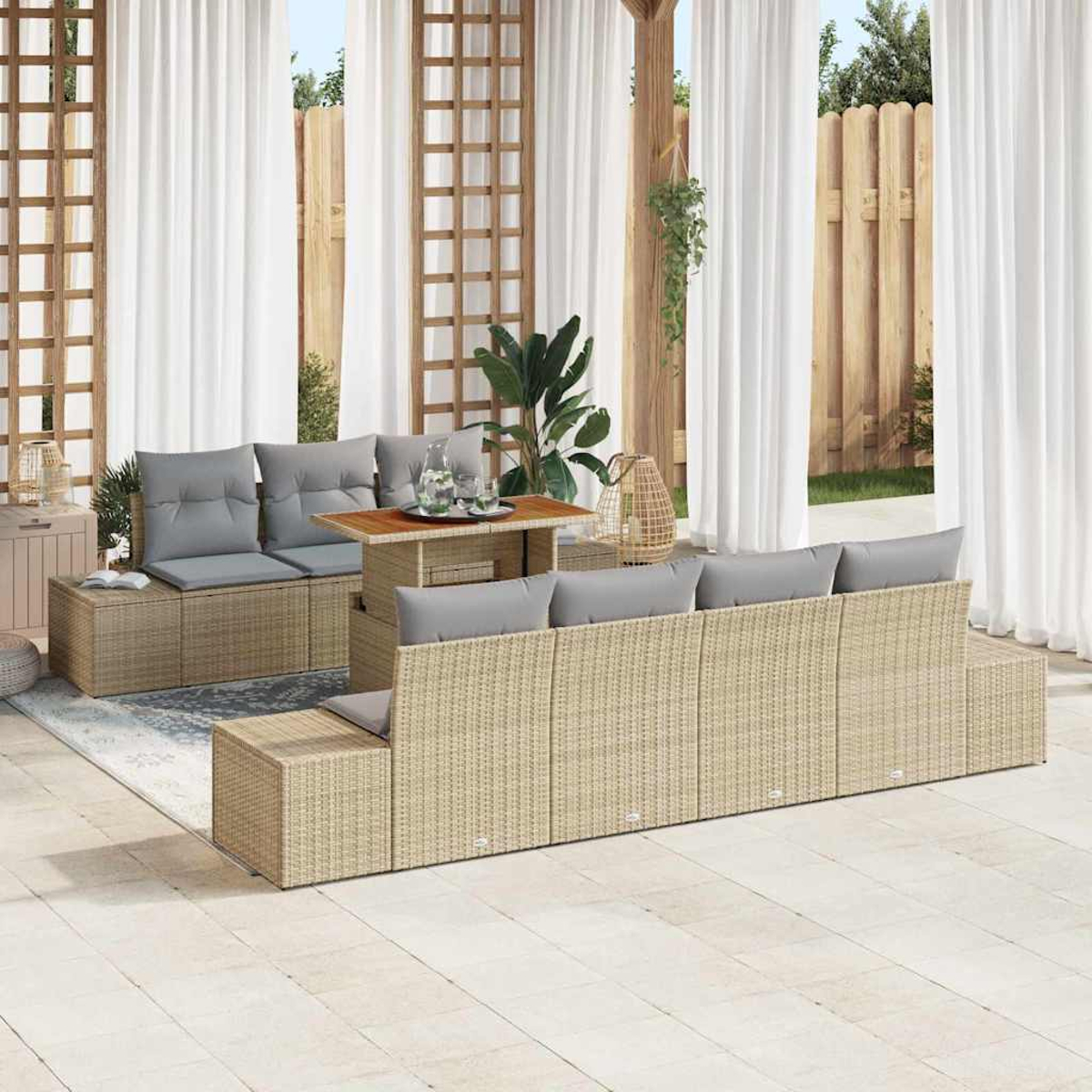 Terrassenset mit beigen Korbmöbeln, grauen Kissen, Holztisch, weißen Vorhängen und Holzzaun im Hintergrund.