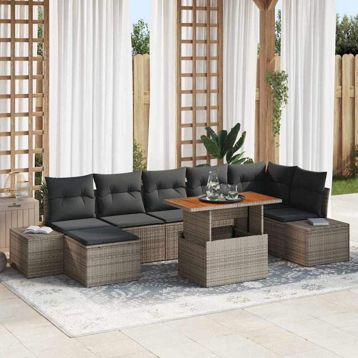 Garten-Terrassenset mit grauen Kissen. Holztisch mit Gläsern und einer Kanne. Weiße Vorhänge und eine Holzkonstruktion im Hintergrund.