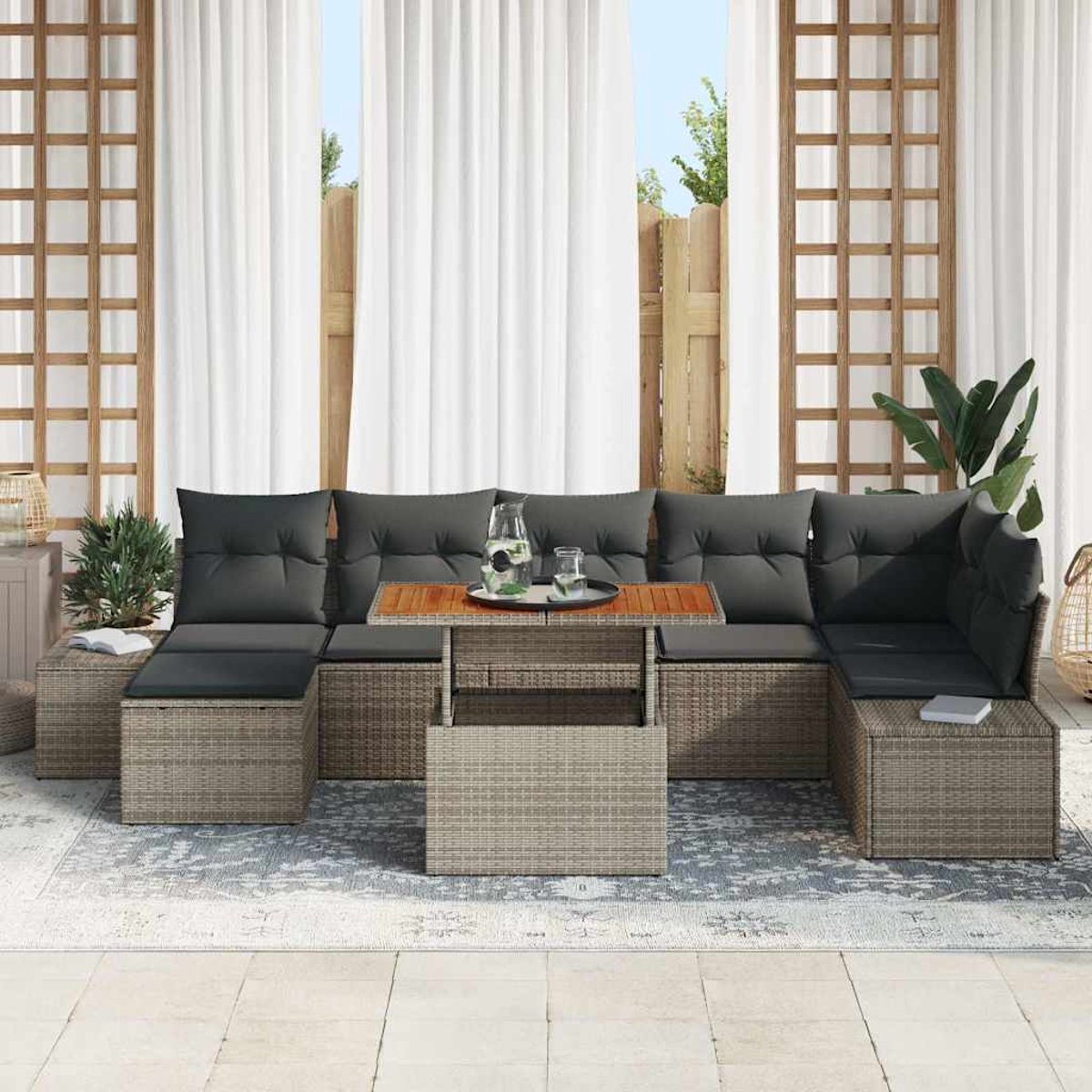 Outdoor-Ecksofa mit grauen Kissen, Holztisch mit Getränken, auf einem Teppich, vor weißen Vorhängen und Holzgitter.