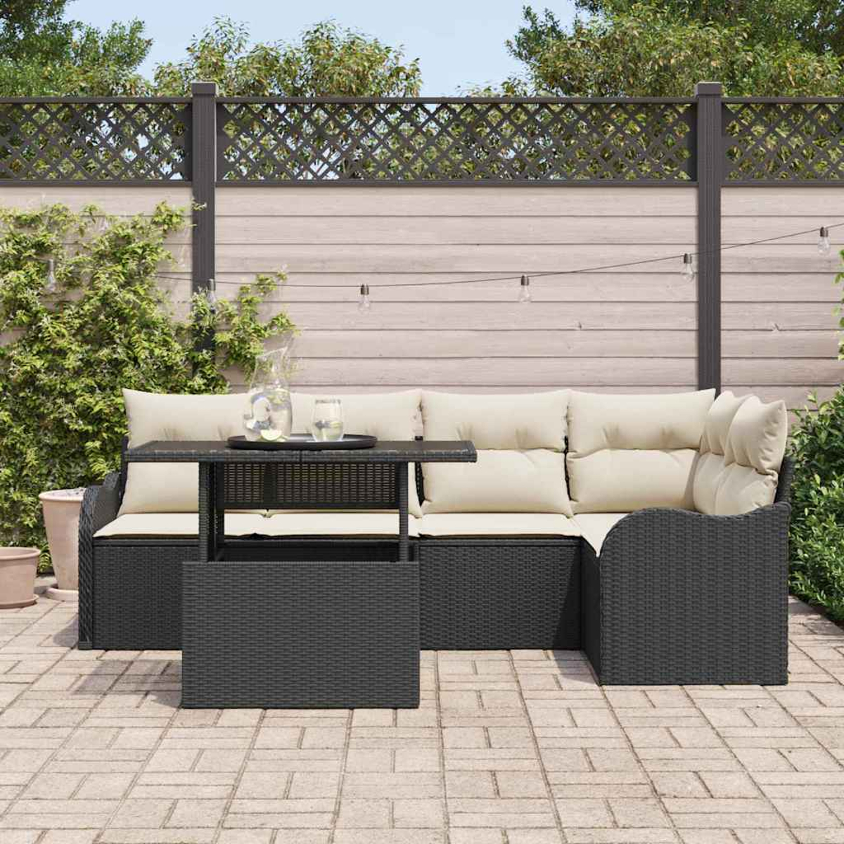 Garten-Terrassenset mit schwarzen Korbmöbeln und cremefarbenen Kissen. Ein Tisch mit Tablett und Getränken steht vor dem Sofa.