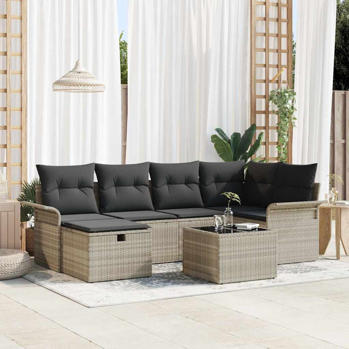 Gartenmöbel-Set: ein grau gepolstertes Sofa, eine Ottomane und ein Couchtisch auf einem Teppich, mit weißen Vorhängen im Hintergrund.