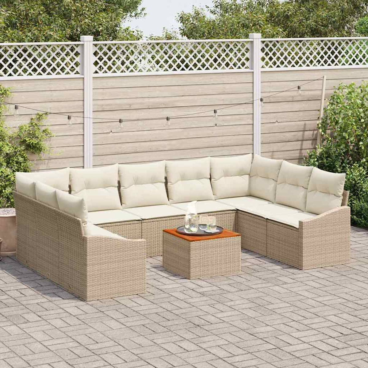 Eine Außenszene mit einem beigefarbenen Ecksofa und Couchtisch aus Korbgeflecht. Im Hintergrund sind ein Zaun und Grün zu sehen. Lichterketten hängen.