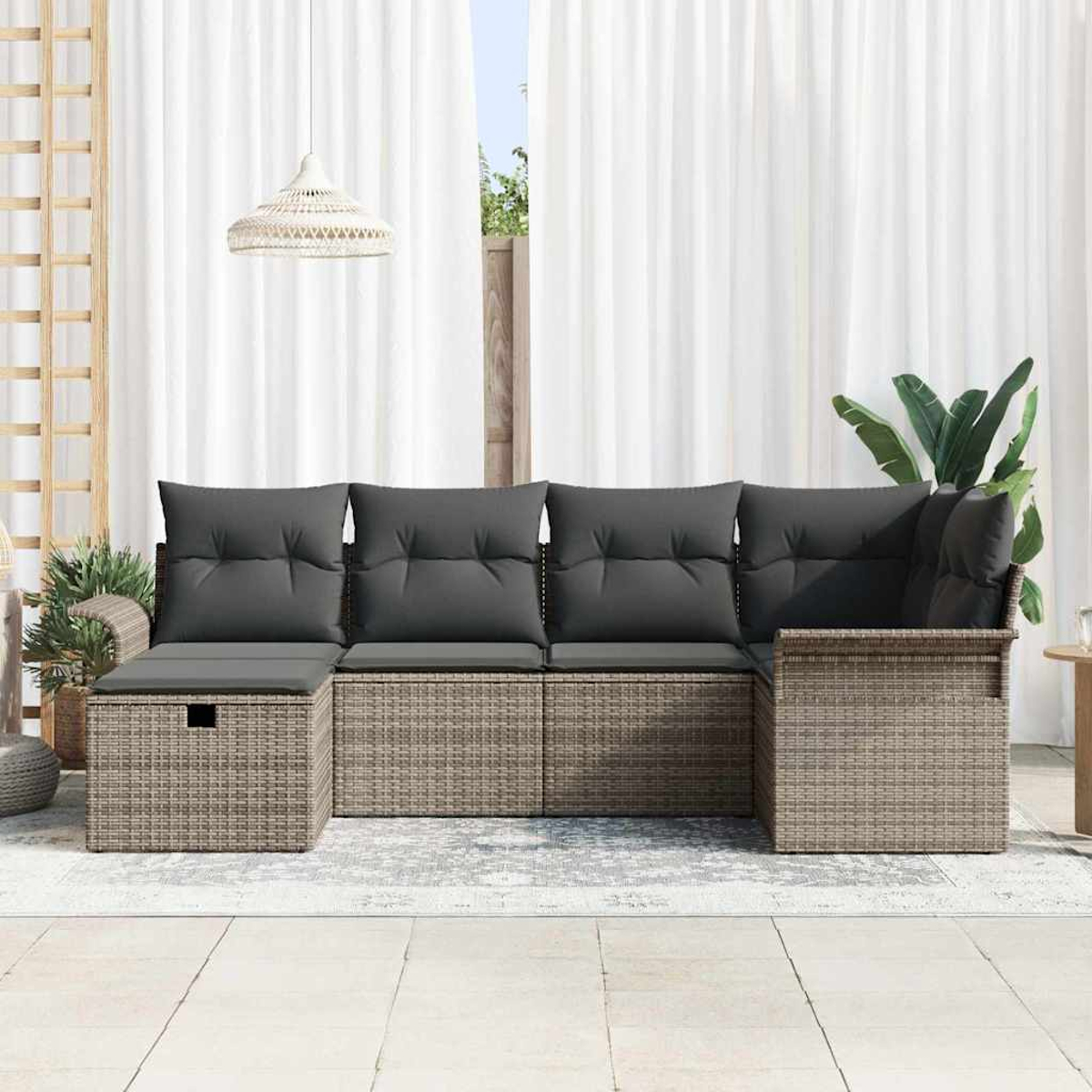 Ein Ecksofa aus Rattan mit grauen Kissen steht auf einer Terrasse. Weiße Vorhänge und eine Hängelampe sind im Hintergrund.