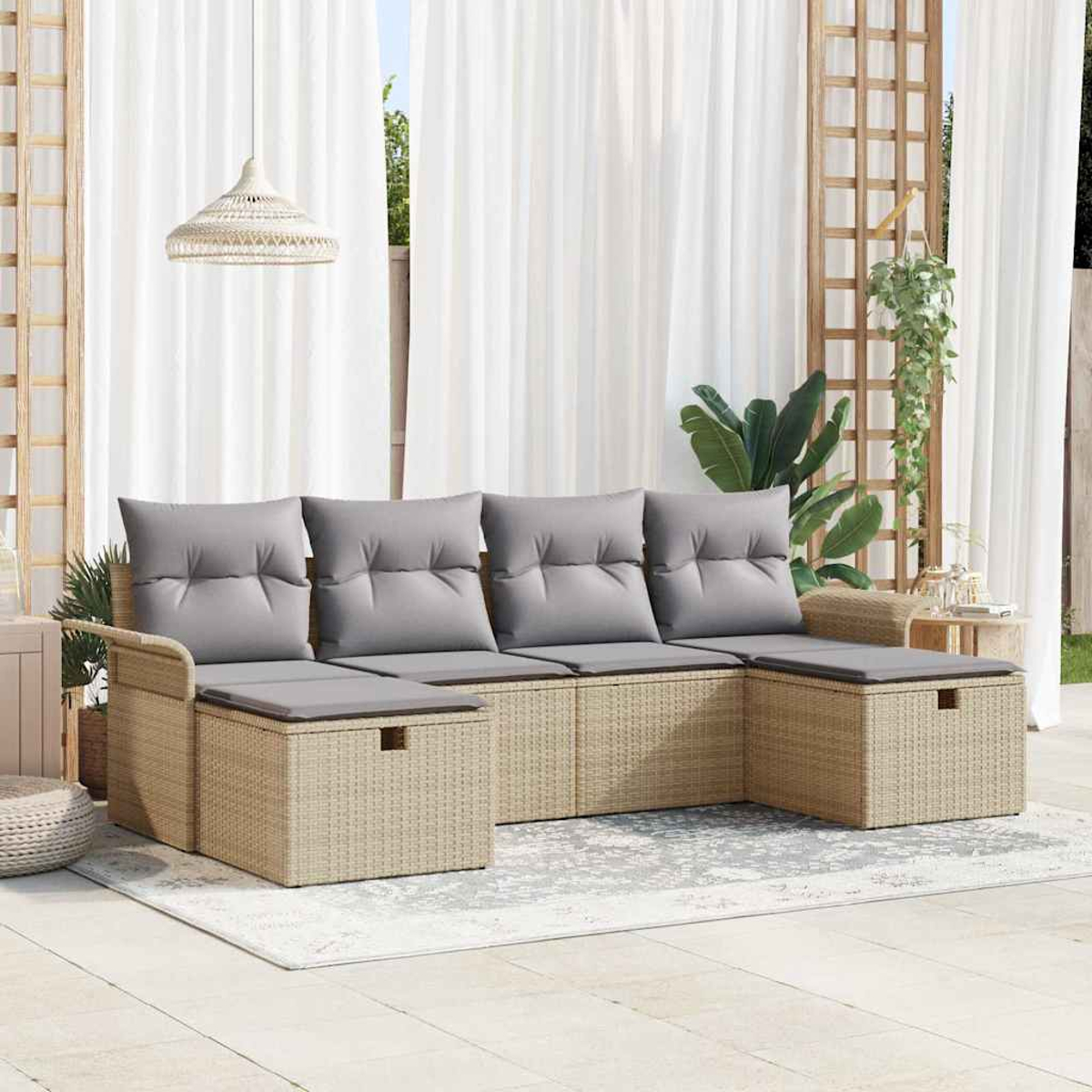 Sofá seccional exterior con cojines grises. Base de mimbre beige, sobre una alfombra. Cortinas blancas y un enrejado de madera al fondo.