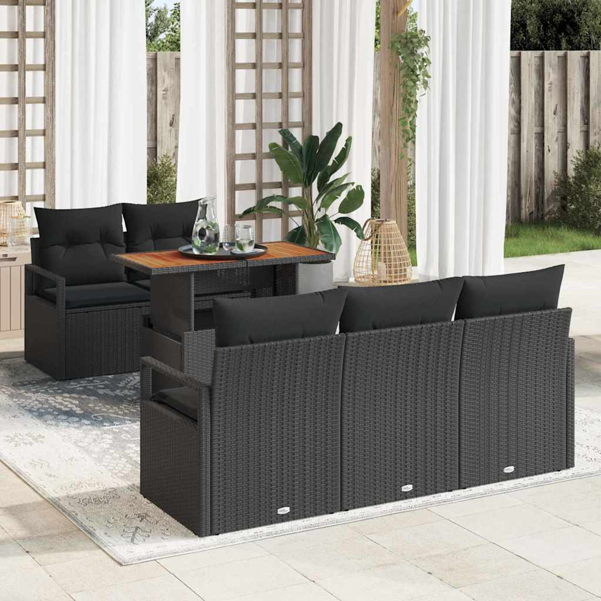 Gartenmöbel-Set mit schwarzem Rattansofa, Stühlen und Tisch. Weiße Vorhänge und Pflanzen im Hintergrund.