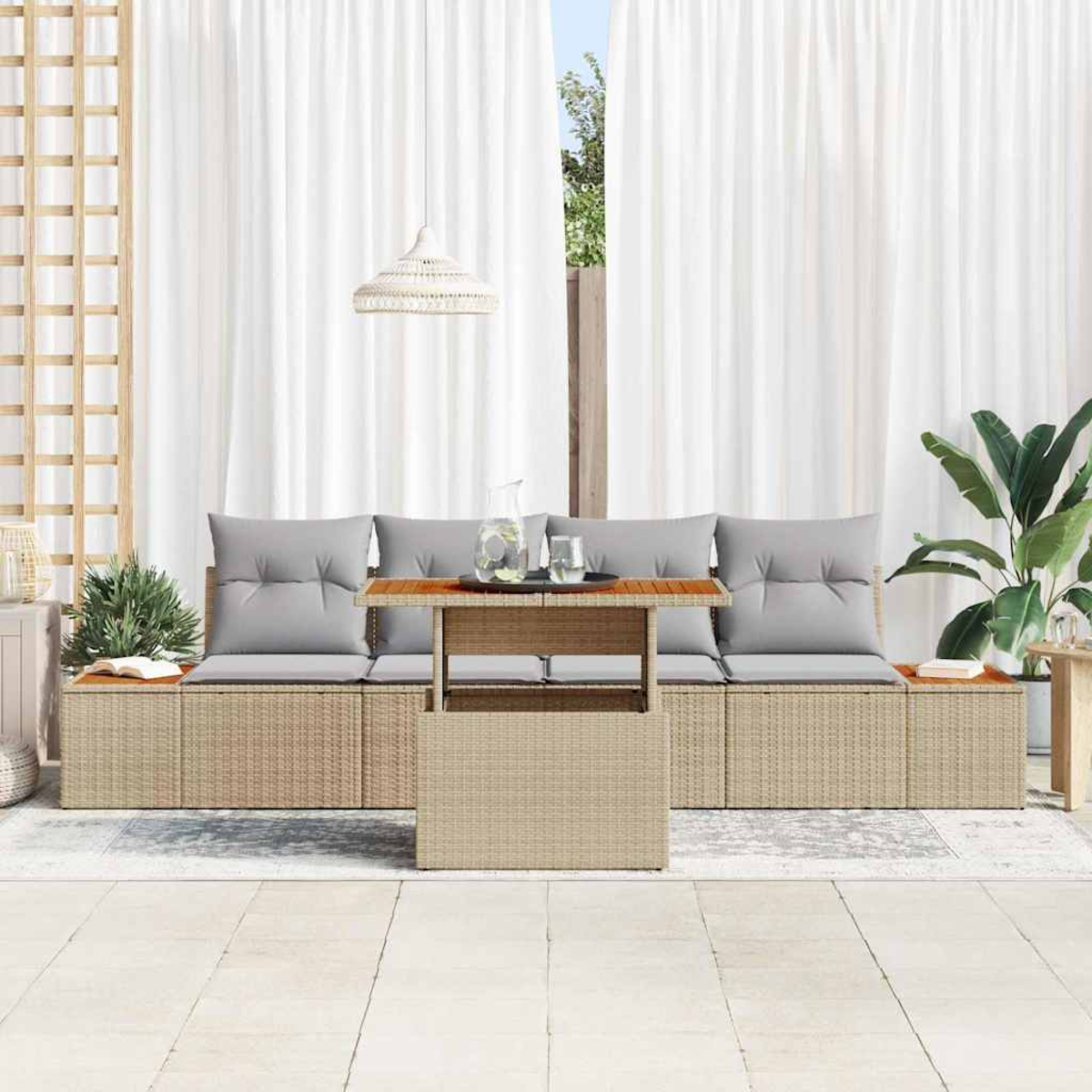 Sitzbereich im Freien mit einem Rattan-Sofa, grauen Kissen, Holztisch und weißen Vorhängen.