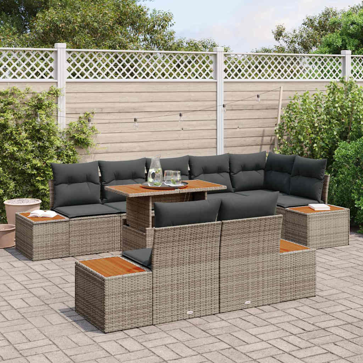 Terrassenset mit grauen Kissen und Holztischplatten. Beinhaltet Sofa, Stühle und Tisch vor Zaun und Grün.