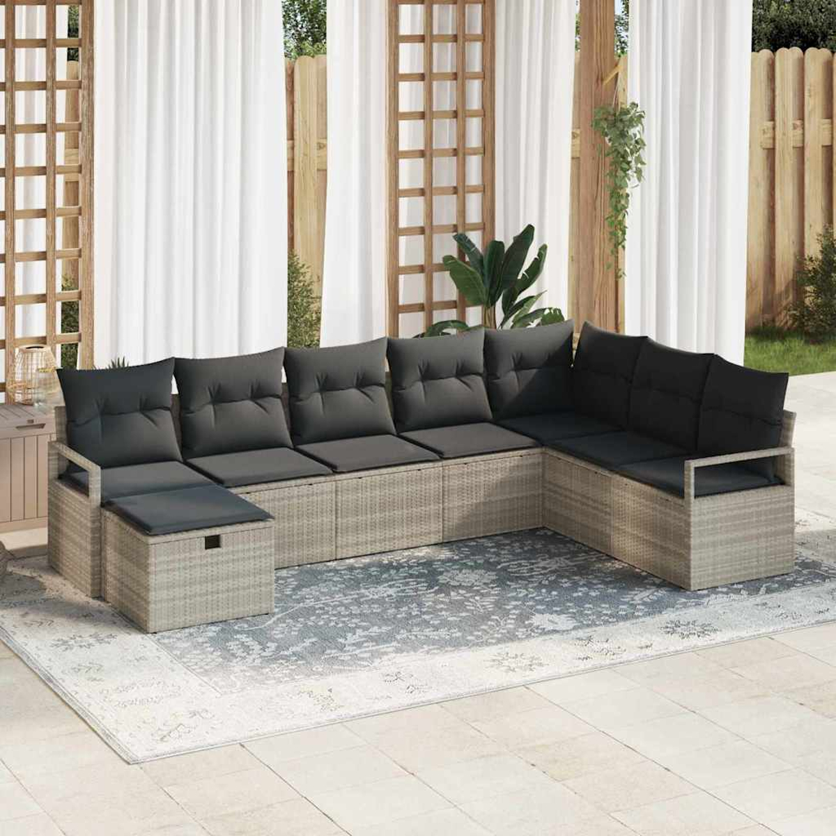 Outdoor-Ecksofa mit grauen Kissen auf einem gemusterten Teppich. Weiße Vorhänge und Holzstruktur im Hintergrund.
