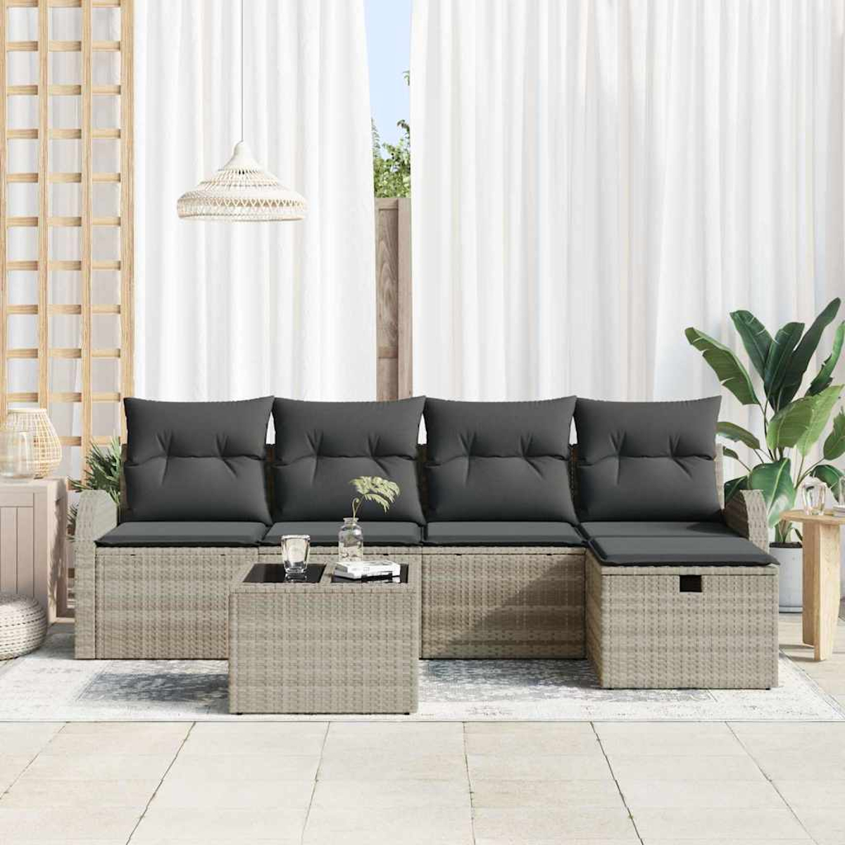 Garten-Sitzgruppe mit grauen Kissen, kleinem Tisch mit Glas, weißen Vorhängen und einer Pflanze.