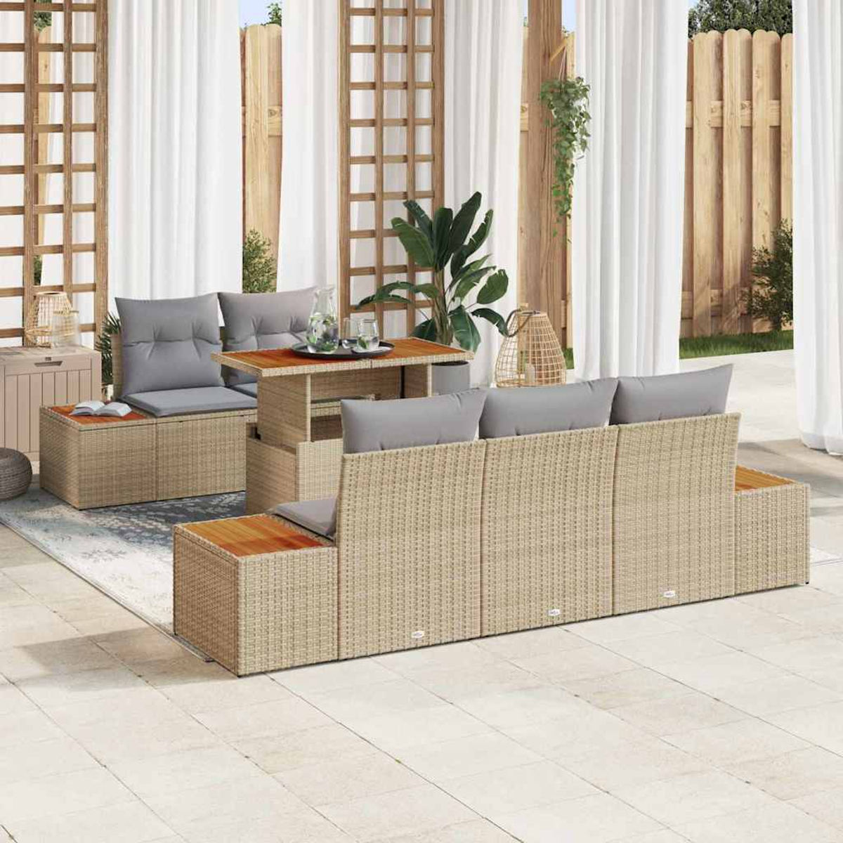 Juego de sofás de mimbre para exteriores con cojines grises, mesa de madera y almacenamiento. Cortinas blancas y valla de madera al fondo.