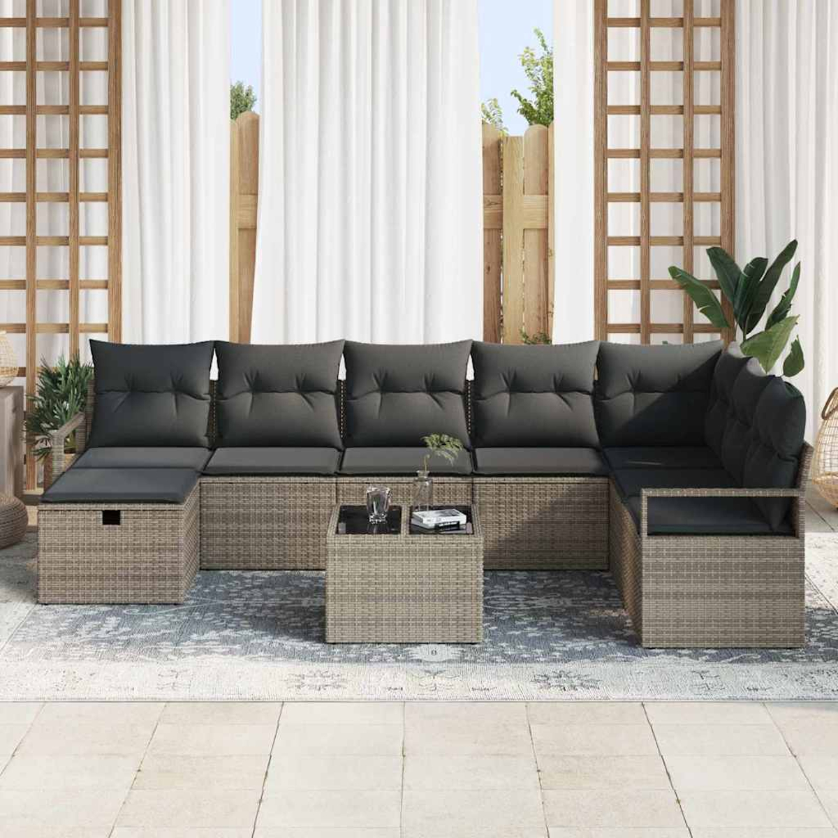 Garten-Ecksofa mit grauen Kissen und einem kleinen Tisch. Weiße Vorhänge und hölzerner Spalier im Hintergrund. Teppich auf dem Boden.