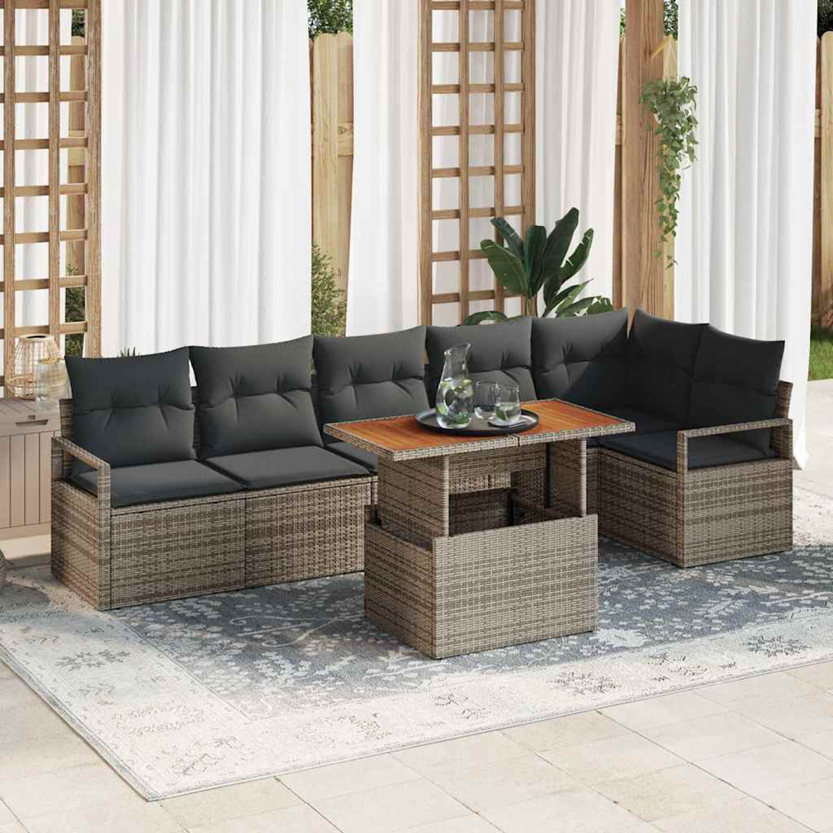 Gartenmöbel-Set mit grauen Kissen und einem Holztisch. Das Set steht auf einem gemusterten Teppich vor weißen Vorhängen.