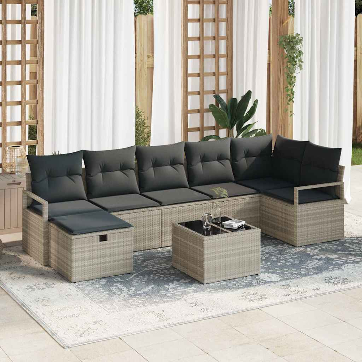 Outdoor-Ecksofa mit dunkelgrauen Kissen. Vorne steht ein kleiner Tisch mit Gläsern. Vorhänge und Gitter im Hintergrund.