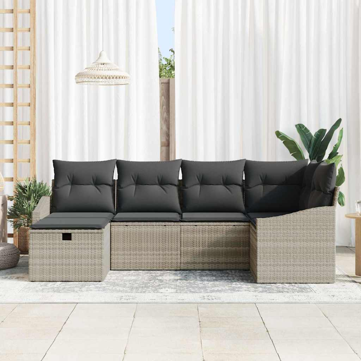 Wicker-Sofa mit grauen Kissen. Weiße Vorhänge und eine Hängelampe im Hintergrund. Pflanzen und ein Teppich auf der Terrasse.