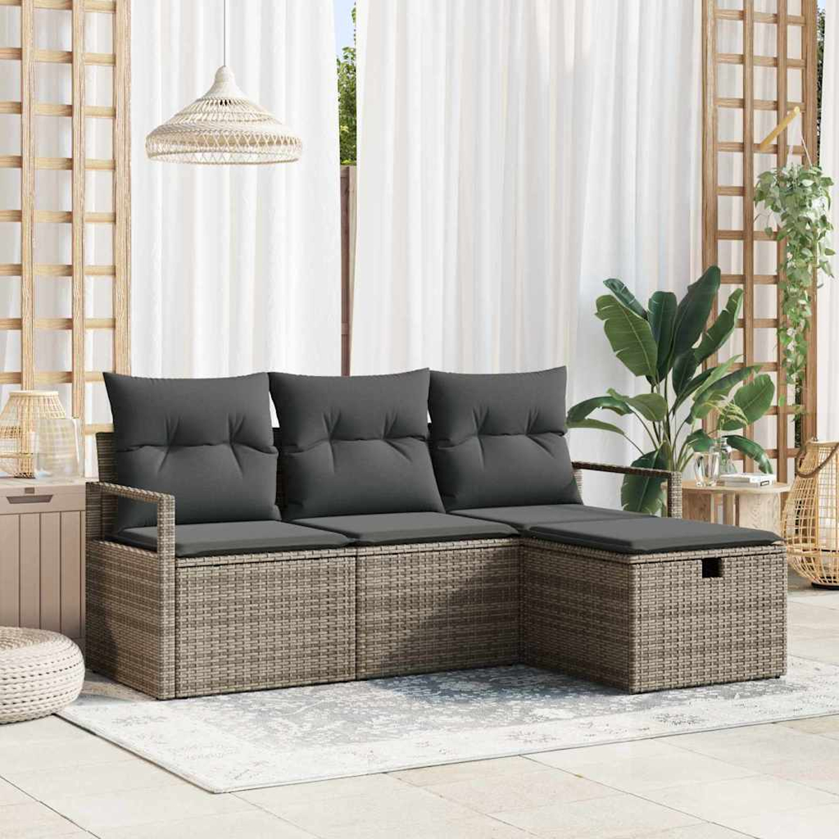 Rattan-Ecksofa mit grauen Kissen auf einer Terrasse. Weiße Vorhänge, Pflanzen und eine Hängeleuchte sind sichtbar.