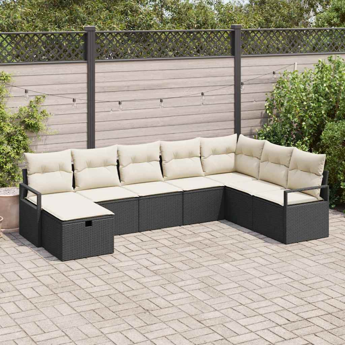 Outdoor-Ecksofa mit cremefarbenen Kissen auf einer Backstein-Terrasse. Im Hintergrund sind ein Zaun, Lichterketten und Grün zu sehen.