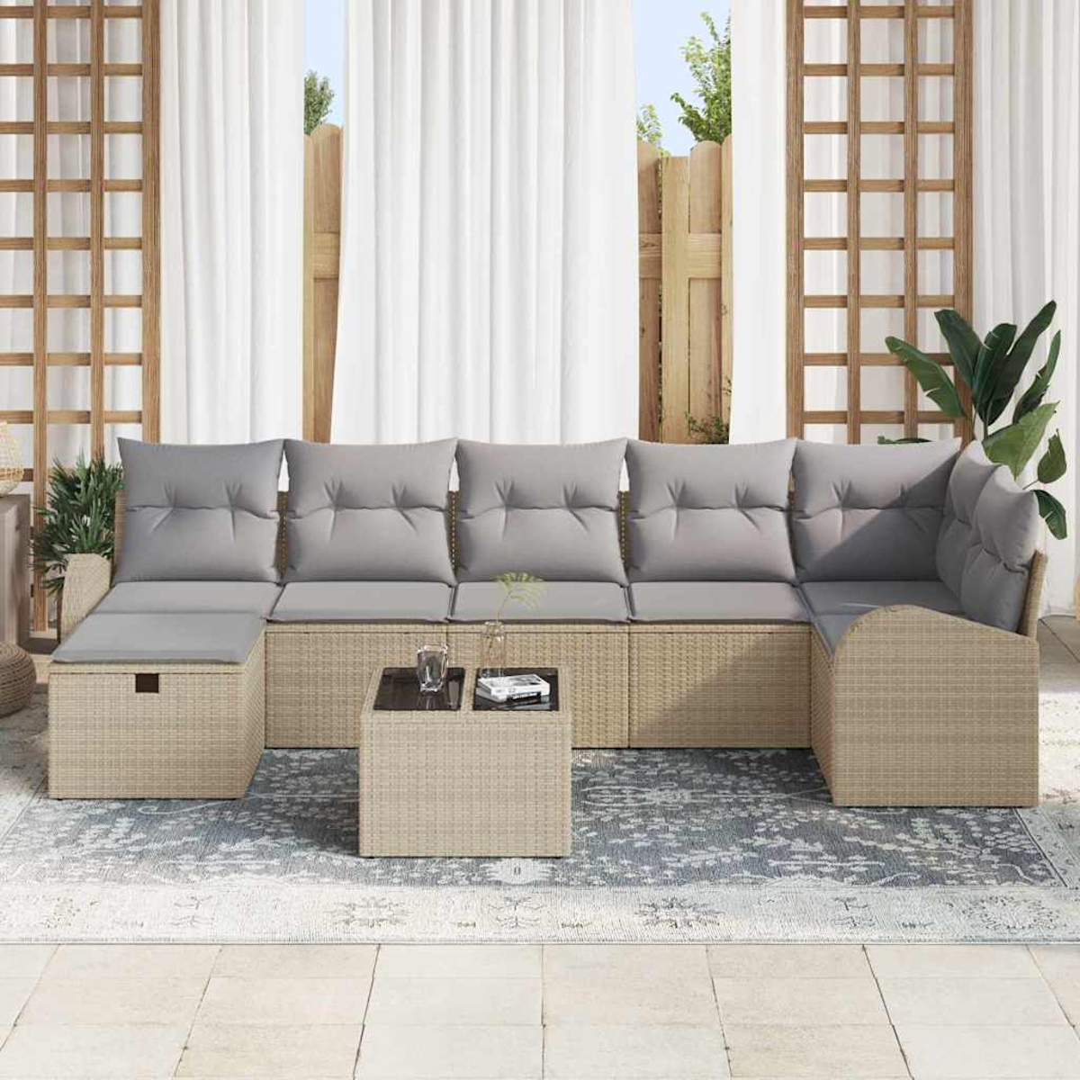 Outdoor-Ecksofa mit grauen Kissen, kleinem Tisch und Teppich. Weiße Vorhänge, Holzzaun und grüne Pflanzen im Hintergrund.