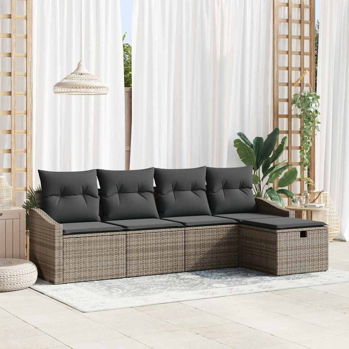 Ein Outdoor-Sofa aus Rattan mit grauen Kissen. Ein weißer Vorhang im Hintergrund, eine Hängelampe und Pflanzen sind sichtbar.
