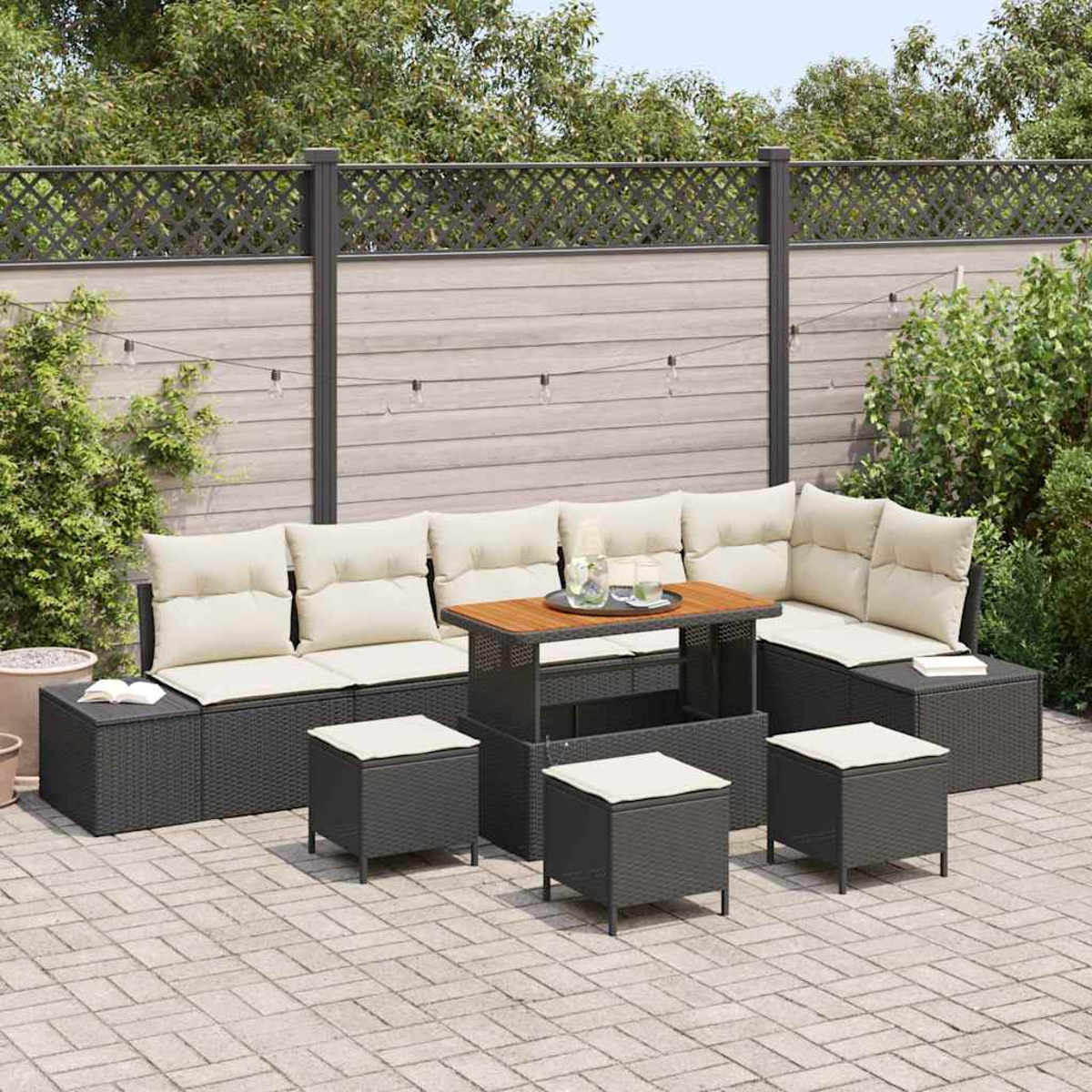 Outdoor-Terrassenset mit dunkelgrauen Korbmöbeln, beigen Kissen und einem Holztisch. Der Hintergrund zeigt einen Zaun und Grün.