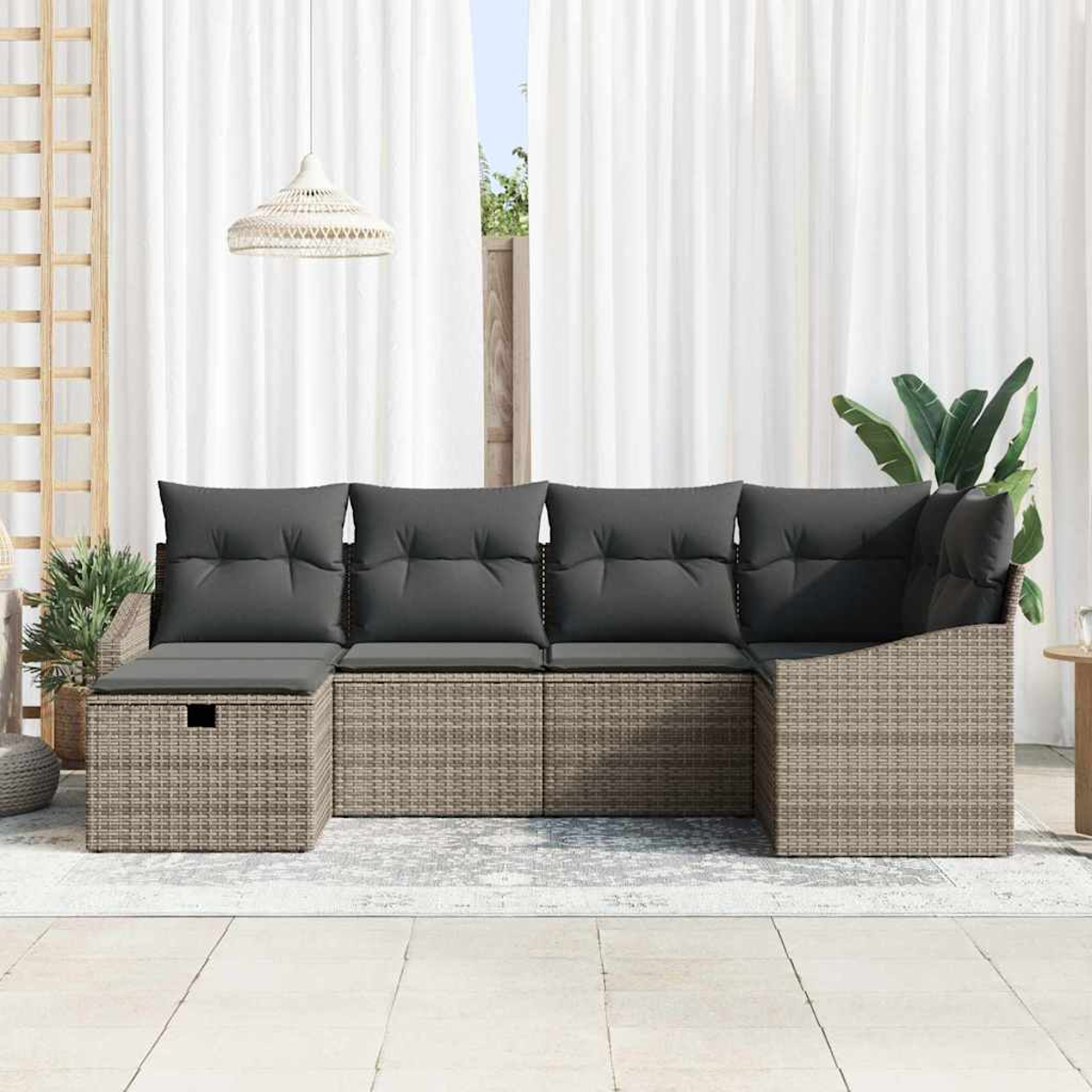 Outdoor-Rattan-Ecksofa mit grauen Kissen. Im Hintergrund ein weißer Vorhang und eine Hängelampe. Rechts eine Pflanze.