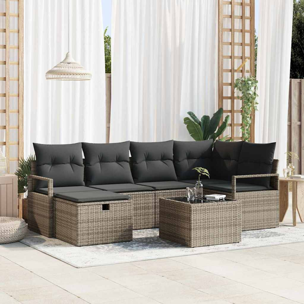 Terrassengarnitur mit grauen Kissen und Möbeln aus geflochtenem Rattan. Enthält einen Couchtisch und eine Hängeleuchte.