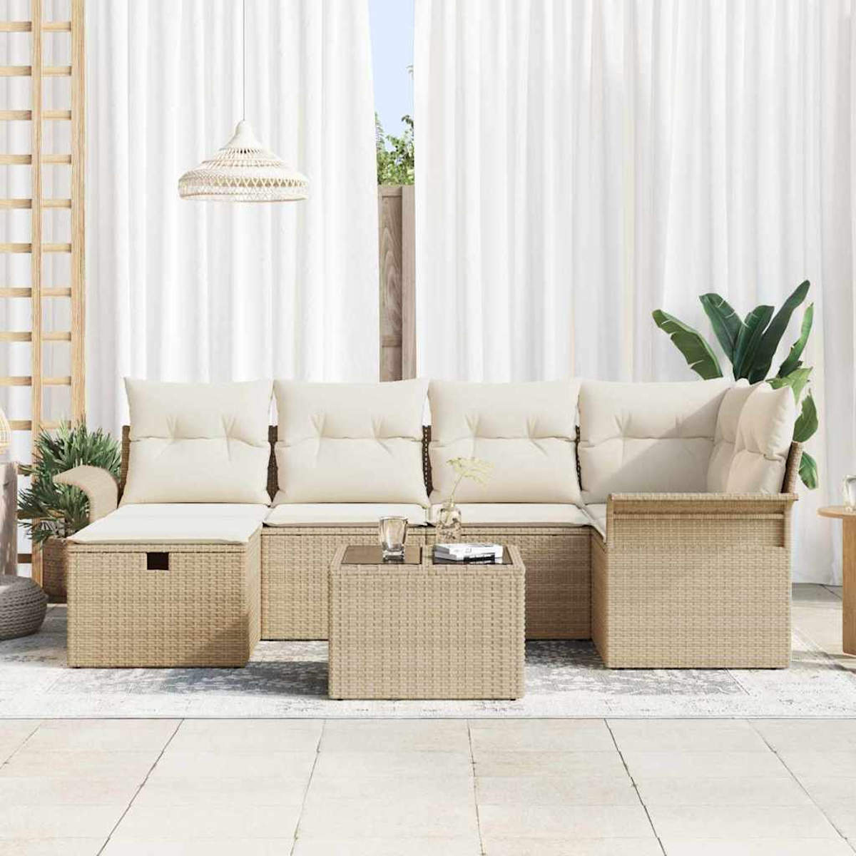 Gartenmöbel-Set aus Korbgeflecht mit cremefarbenen Kissen. Enthält ein Sofa, einen Couchtisch und eine Hängeleuchte vor weißen Vorhängen.